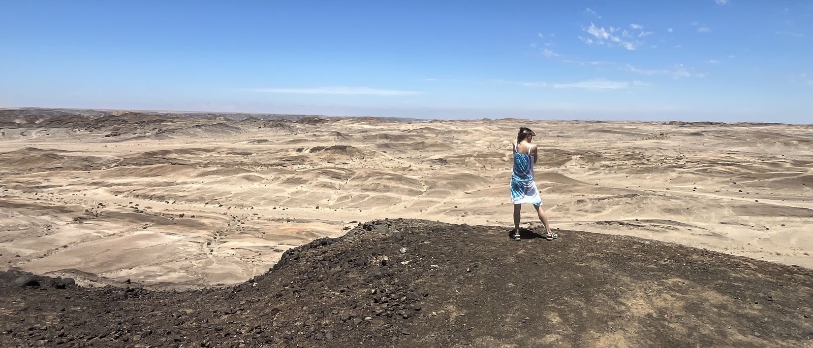 Kathleen Schütz steht klein auf einem Grat vor der weiten Wüstenlandschaft Namibias